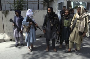 Taliban fighters stand guard at the main gate leading to the Afghan presidential palace after taking control of the capital