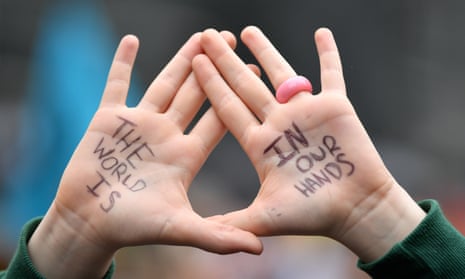 A school student's hold their hands up with the words 'The world is in our hands' written ontheir palms at a School Strike 4 Life protest in Sydney on Friday, May 21, 2021