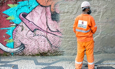An employee of the Cidade Linda programme paints over street art in São Paulo.