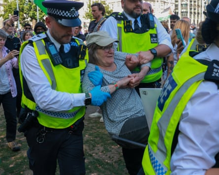 A woman being carried away by two police officers