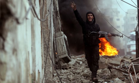 A Free Syrian Army fighter in front of a burning barricade in Damascus