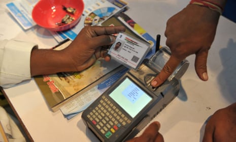 An Indian man gives a thumb impression to withdraw money from his bank account with his Aadhaar card in Hyderabad.