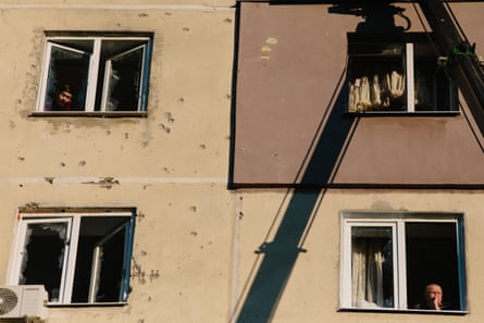 People look through the shattered windows of their apartments