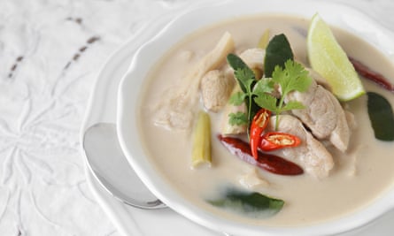 Semangkuk tom kha gai, sup ayam dan kelapa Thailand yang kental, di atas permukaan putih.