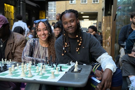 Yusuf Ntahilaja (right) and Lucia One-Lesikar smiling for a photo at a table with a chessboard on it.