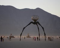 Aa sparse crowd in front of an art structure in the desert with a mountain backdrop