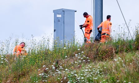 Workers in orange work clothing working on a grassy verge