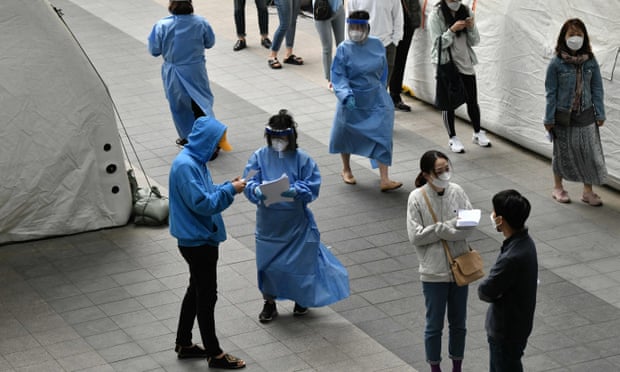 Medical staff deal with visitors waiting to be tested at a coronavirus testing station in Seoul, South Korea