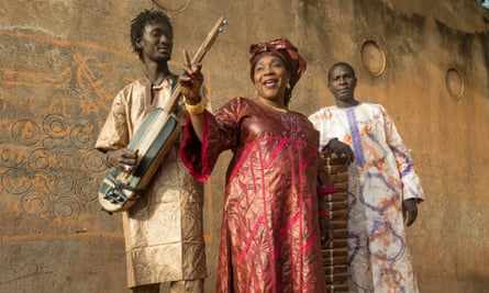 A woman and man wearing African-print clothes and holding Malian instruments