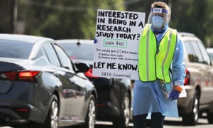 A worker carries a sign asking for participants to join a research study at a drive-in COVID-19 testing site amid the coronavirus pandemic on June 29, 2020 in Los Angeles, California.