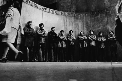 Black and white photo shows members of the Black Panthers standing in a line with their arms folded during a demonstration outside the city courthouse, New York City, April 11, 1969.