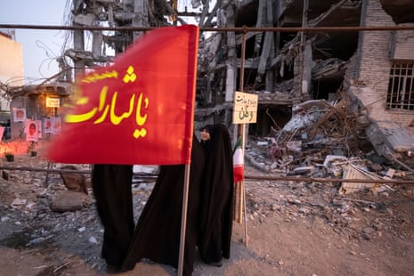 Pro-government supporters gather in front of the ruins of a building in a residential area that was struck during a US-Israeli military operation in Tehran, Iran.