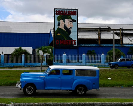 Old cars ride past a billboard with a portrait of the late Cuban leader Fidel Castro that reads in Spanish ‘Socialism or Death’.