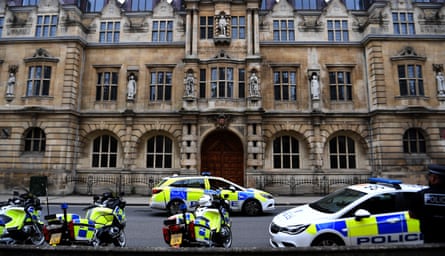 Police stand guard outside Cecil Rhodes statue on the facade of the Oriel College in Oxford, 12 June.
