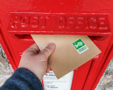 A person posting a letter in a post box.