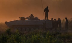Silhouette of an armoured vehicle and soldiers in a field at sunset