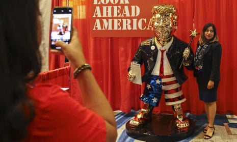An attendee takes a photo with a golden Donald Trump statue at the CPAC conference on Friday.