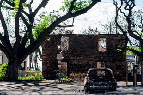 A destroyed car in front of a burned building