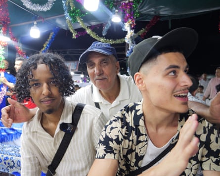 Two young men in a busy street with an older man behind them