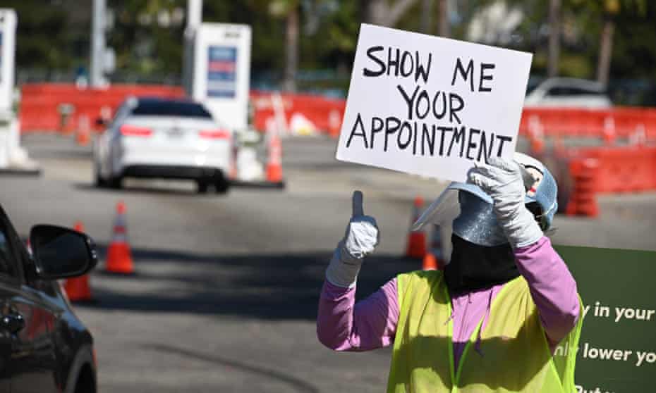 A worker gestures to an arriving car at a coronavirus testing site at Dodger Stadium in Los Angeles, California.