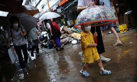 A boy walks through a market under an umbrella