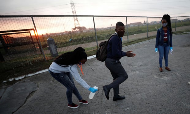 A teacher sanitizes the shoes of a student as schools begin to reopen in Cape Town, South Africa.