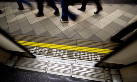 mind the gap sign on london underground tube network with closing doors and commuters streaming past on platform.
