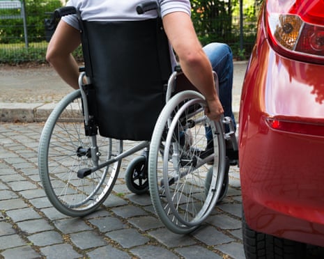 A man in a wheelchair about to get into his car.