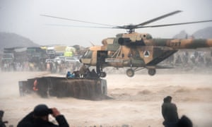 An Afghan military helicopter rescues people clinging to the top an overturned truck in flooded area of Arghandab district in Kandahar province.