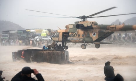 An Afghan military helicopter rescues people clinging to the top an overturned truck in flooded area of Arghandab district in Kandahar province. 