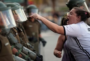 Santiago, Chile. A woman argues with a riot police officer during an anti-government protest