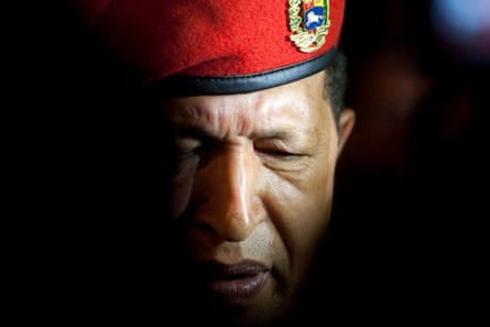 A closeup shot of Hugo Chávez in red military beret, half of his face cast in shadow