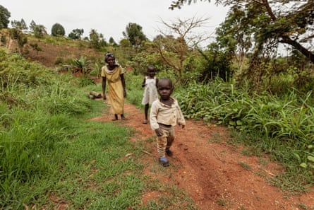 A mother and two young children walk along a forest path