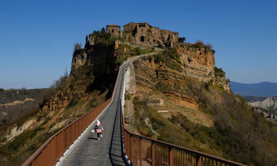 A child runs towards the entrance to the town of Civita di Bagnoregio, accessible only by a bridge.