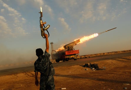 A rebel fighter celebrates as his comrades fire a rocket barrage toward the positions of troops loyal to the Libyan ruler, Muammar Gaddafi, west of Ajdabiyah, Libya on 14 April 2011.