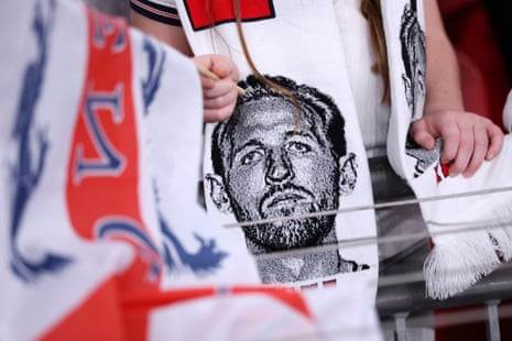 A fan wearing a scarf with the image of Harry Kane of England.