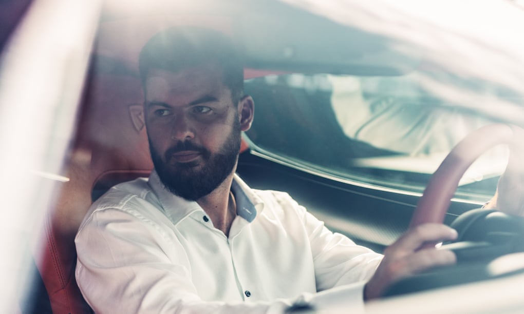 Rimac at the wheel of one of his own cars, photographed through the windscreen, his face surrounded by various reflections