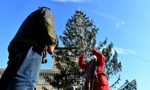 Tourists take pictures near the controversial Christmas tree.
