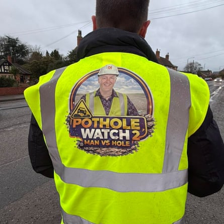 Robert Jenrick faces away from the camera, wearing a bright yellow high vis jacket