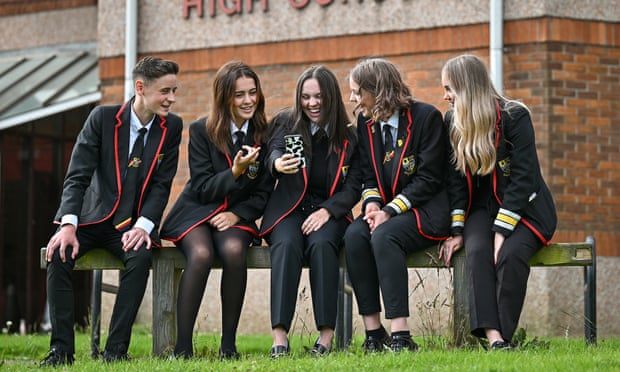 Smiling pupils look at smartphones