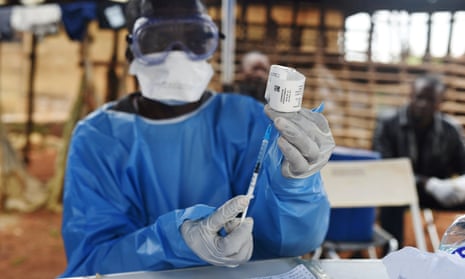 A health worker prepares to administer Ebola vaccine outside a house in the village of Mangina, DRC