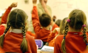 Children in a classroom raise their hands to answer questions