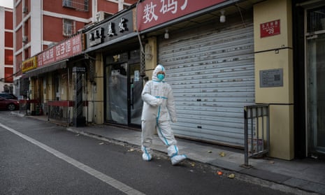 An epidemic control worker walks past closed shops in Beijing on Sunday.