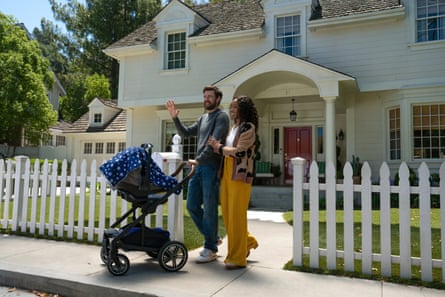 The couple stand with a pushchair outside a house with a wicket fence.