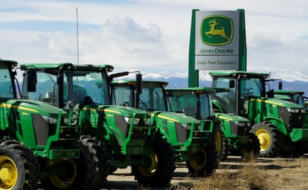 A row of green John Deere tractors on a dealer lot.