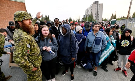 People line up outside of a local school to register to be evacuated, as wildfires threatened Yellowknife.