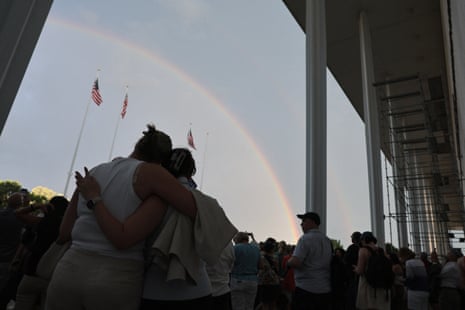 People embraced as a rainbow appeared in the sky over Washington DC late Friday next to scaffolding set up for the removal of Donald Trump’s name from the facade of the John F Kennedy Memorial Center for the Performing Arts.