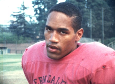 OJ Simpson stares at the camera wearing huge American football padding.