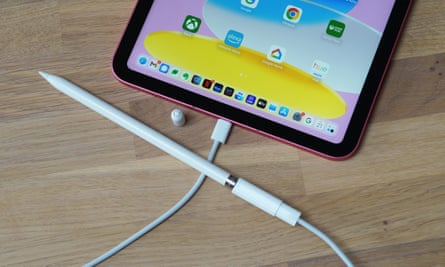 The first-generation Apple Pencil connected to the new iPad via a USB-C cable and Lightning adapter.