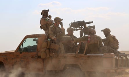 Armed men in uniform identified by Syrian Democratic forces as US special operations forces ride in the back of a pickup truck.